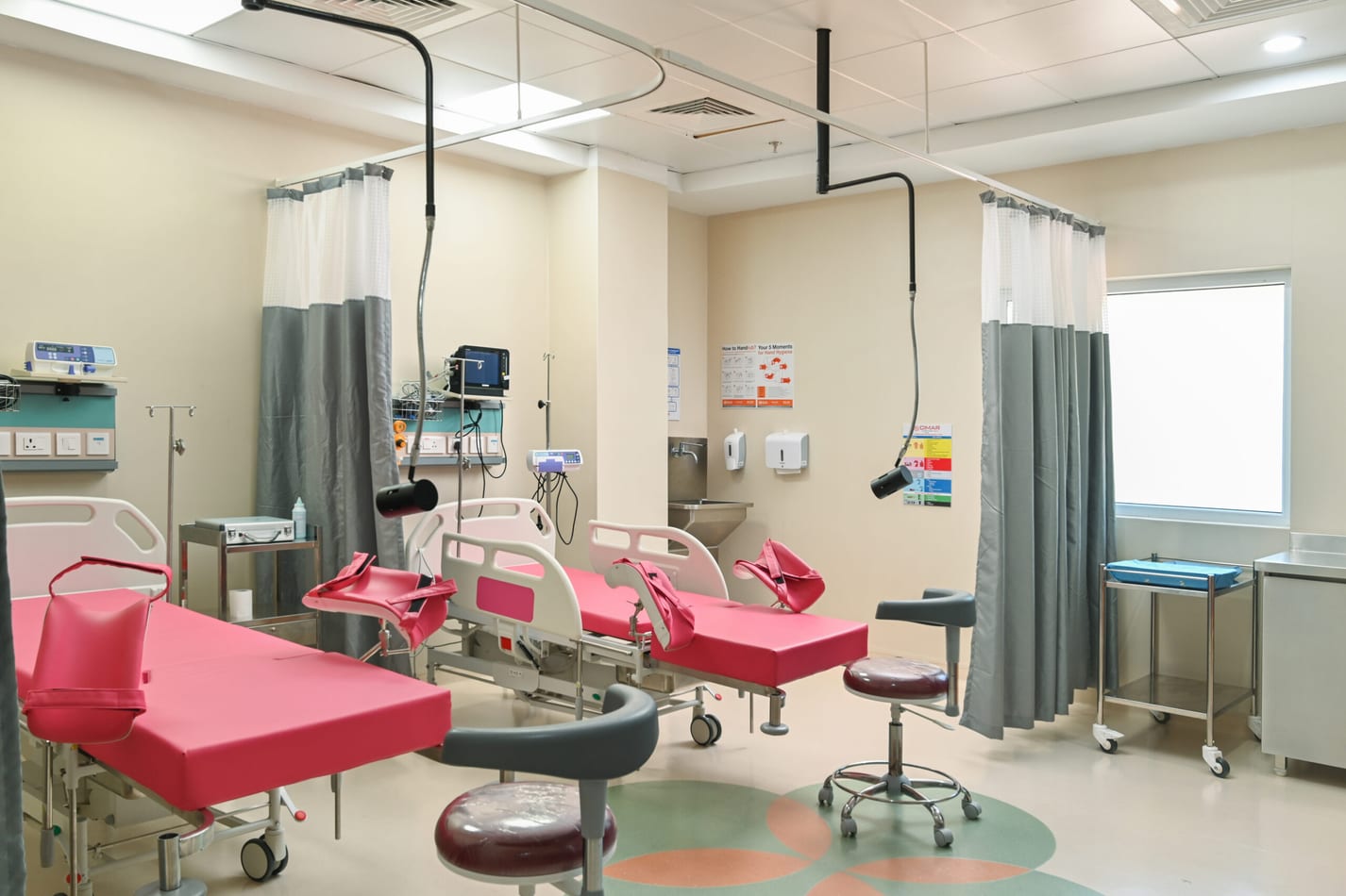 Labour room with pink delivery beds and monitoring equipment